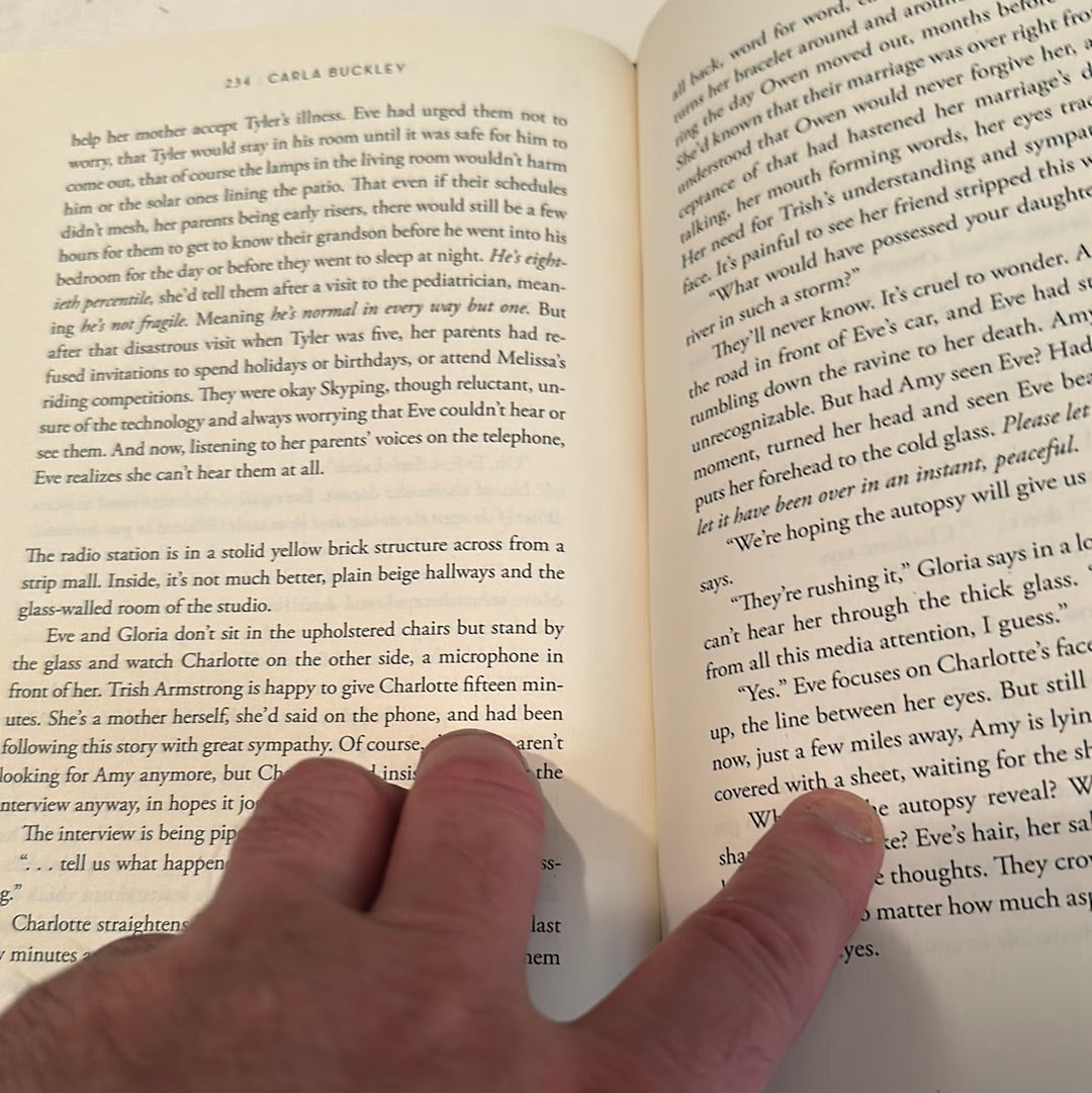 Close-up of hands holding and reading The Deepest Secret novel with visible text pages