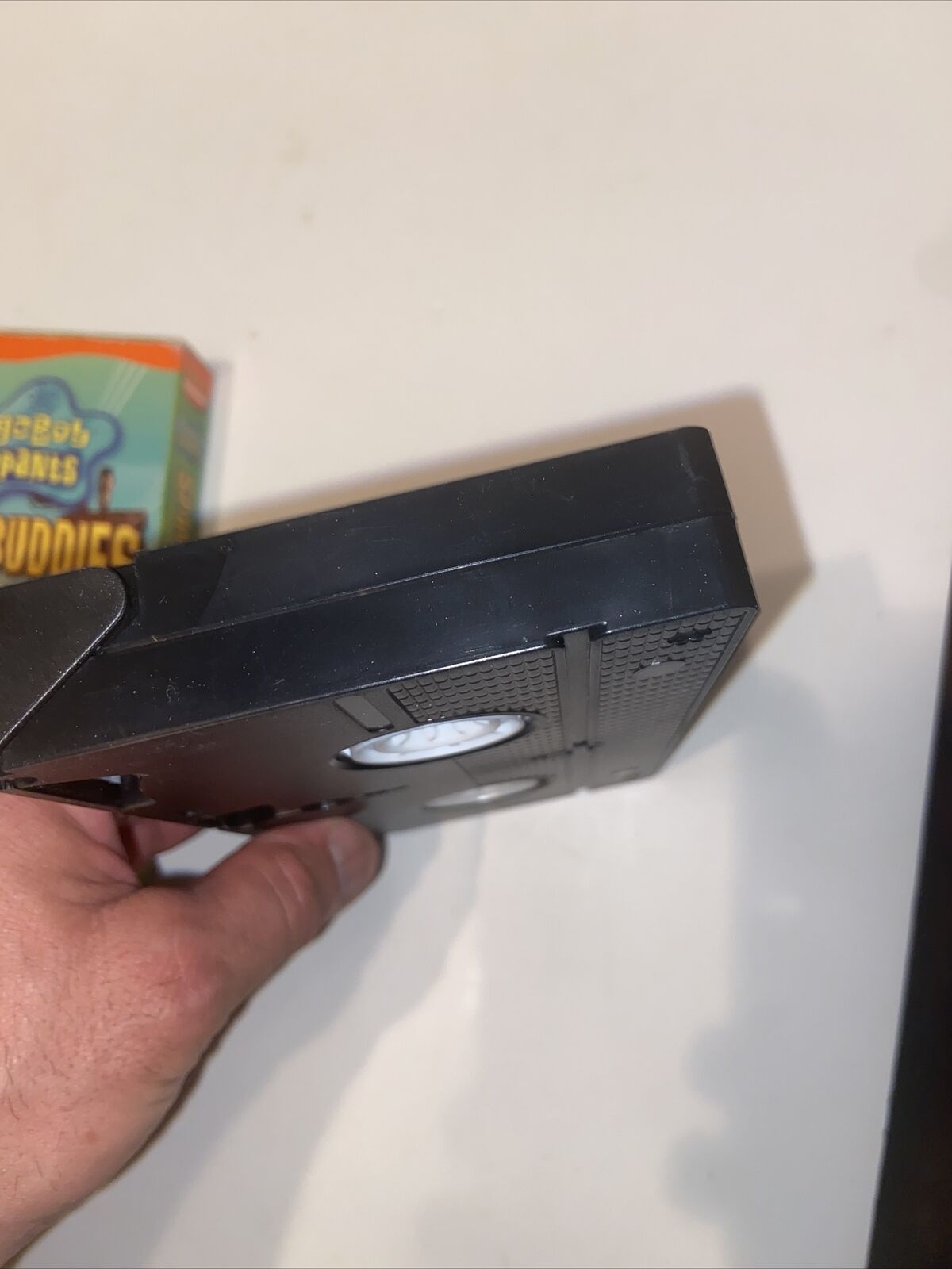 Hand holding black VHS tape with visible Spongebob Sponge Buddies VHS 2002 box art by EveryMailBox