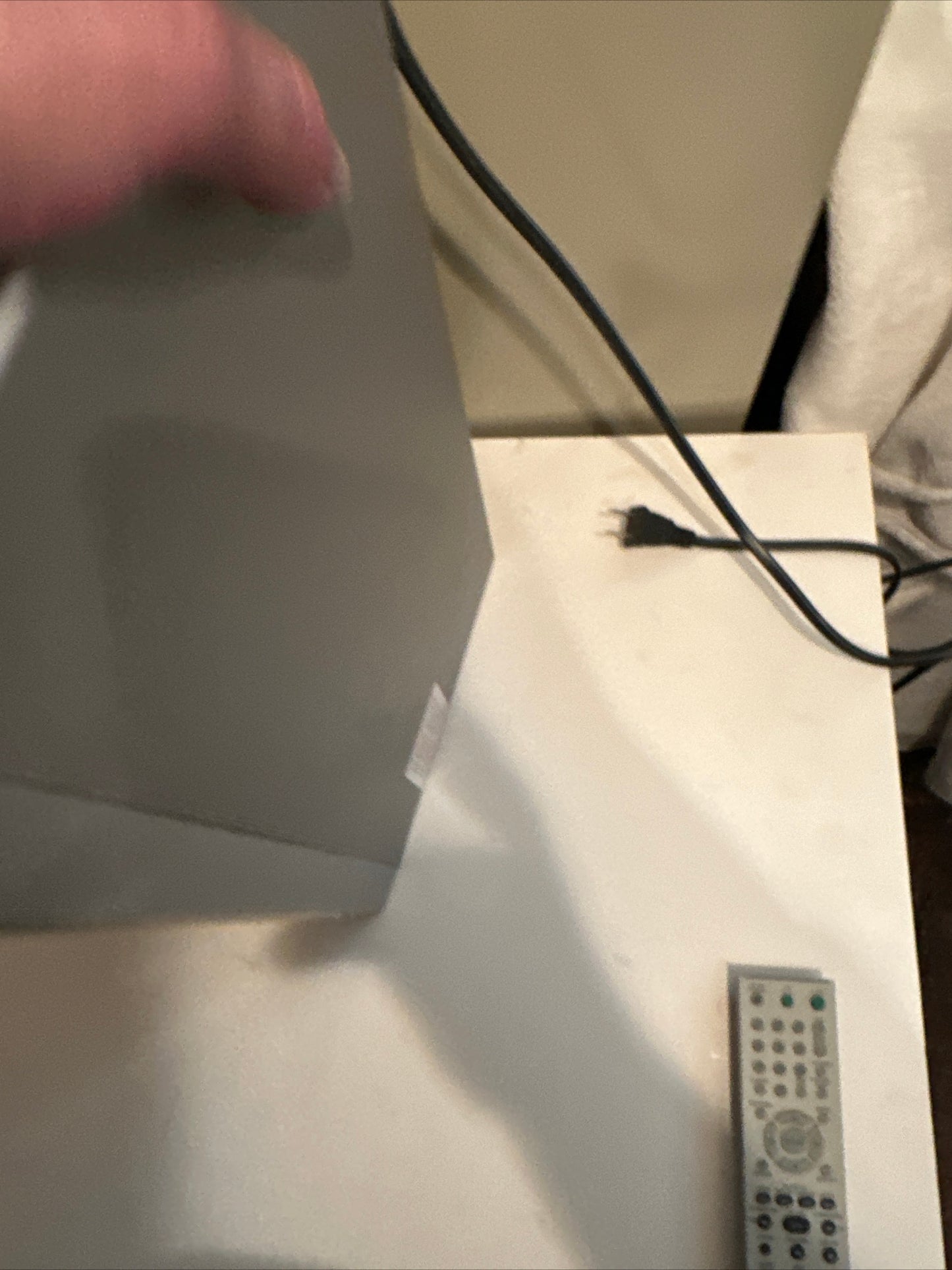 Hand holding a used DVD CD player with remote control on a white surface to buy used DVD CD player online