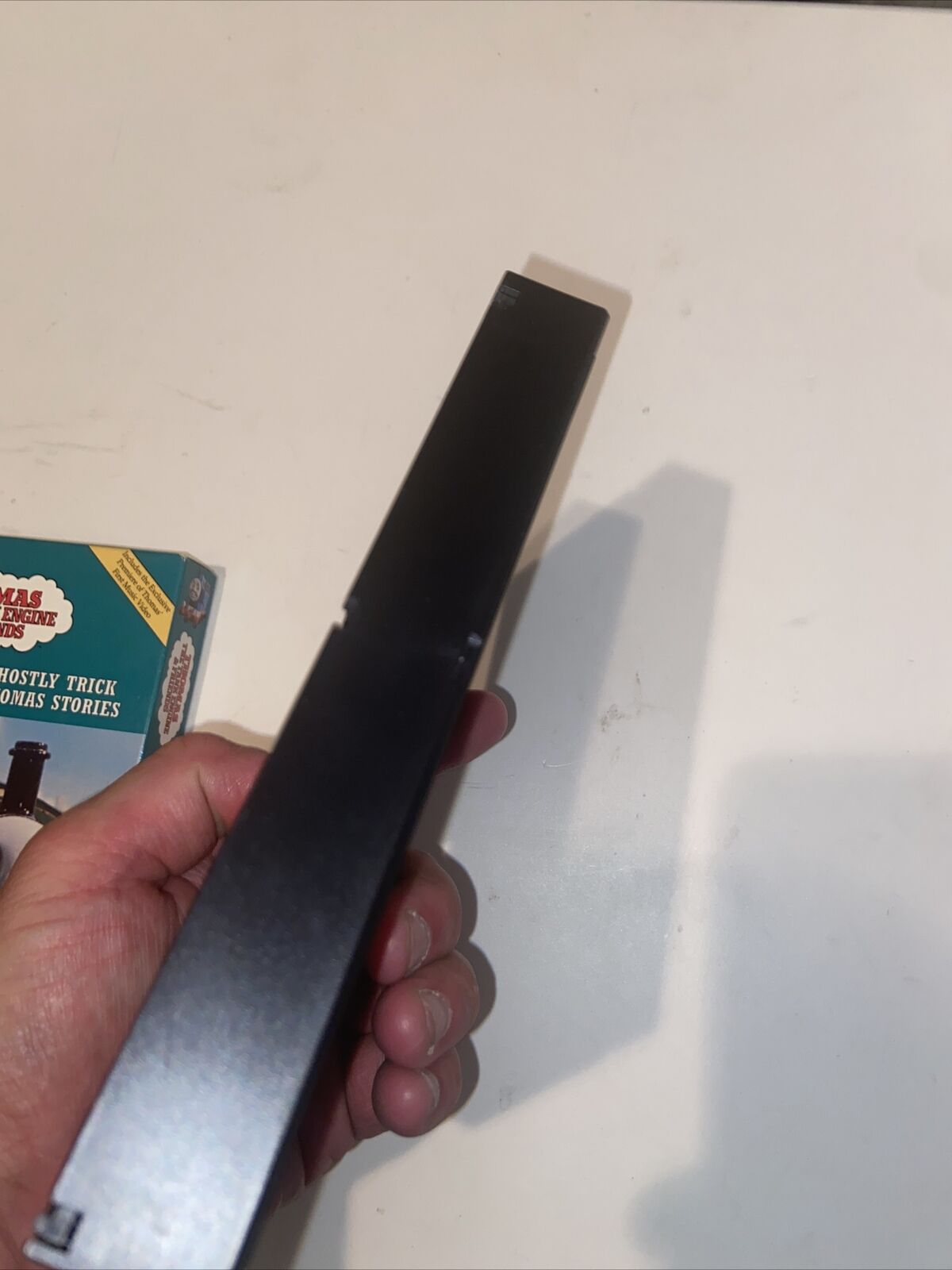 Hand holding black VHS tape spine with Thomas The Tank Engine rare VHS box art corner visible