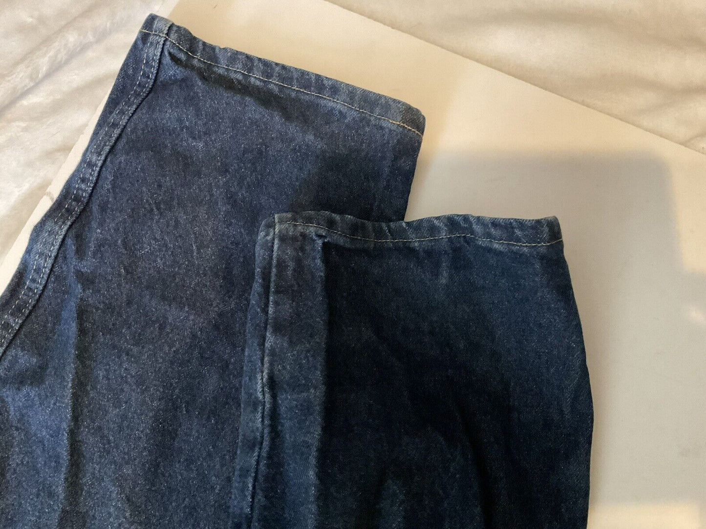 Wrangler relaxed fit jeans men dark wash denim pant legs folded flat showing hems and seams on light surface