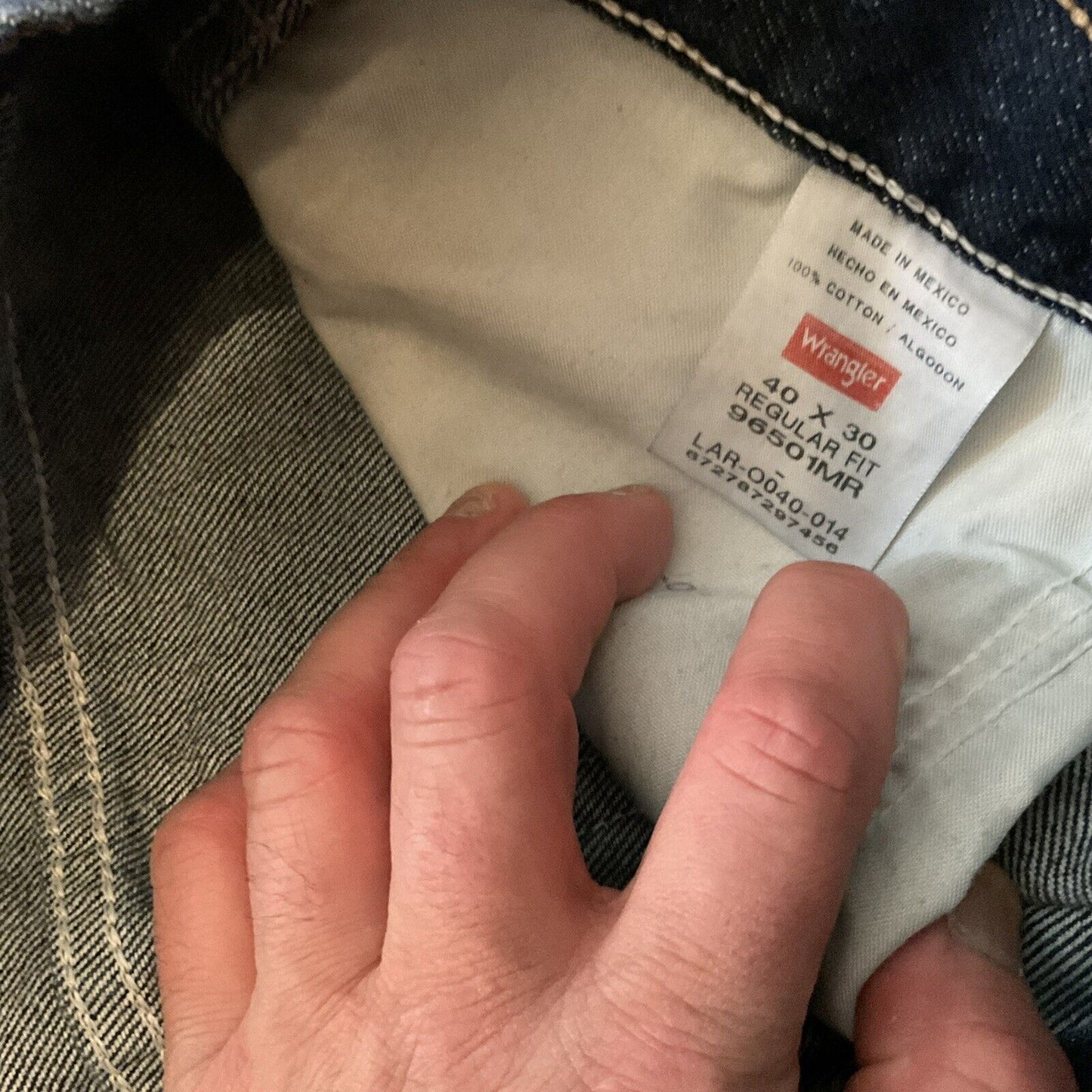 Hand holding inside waistband label of Wrangler relaxed fit jeans men showing size 40x30 regular fit tag