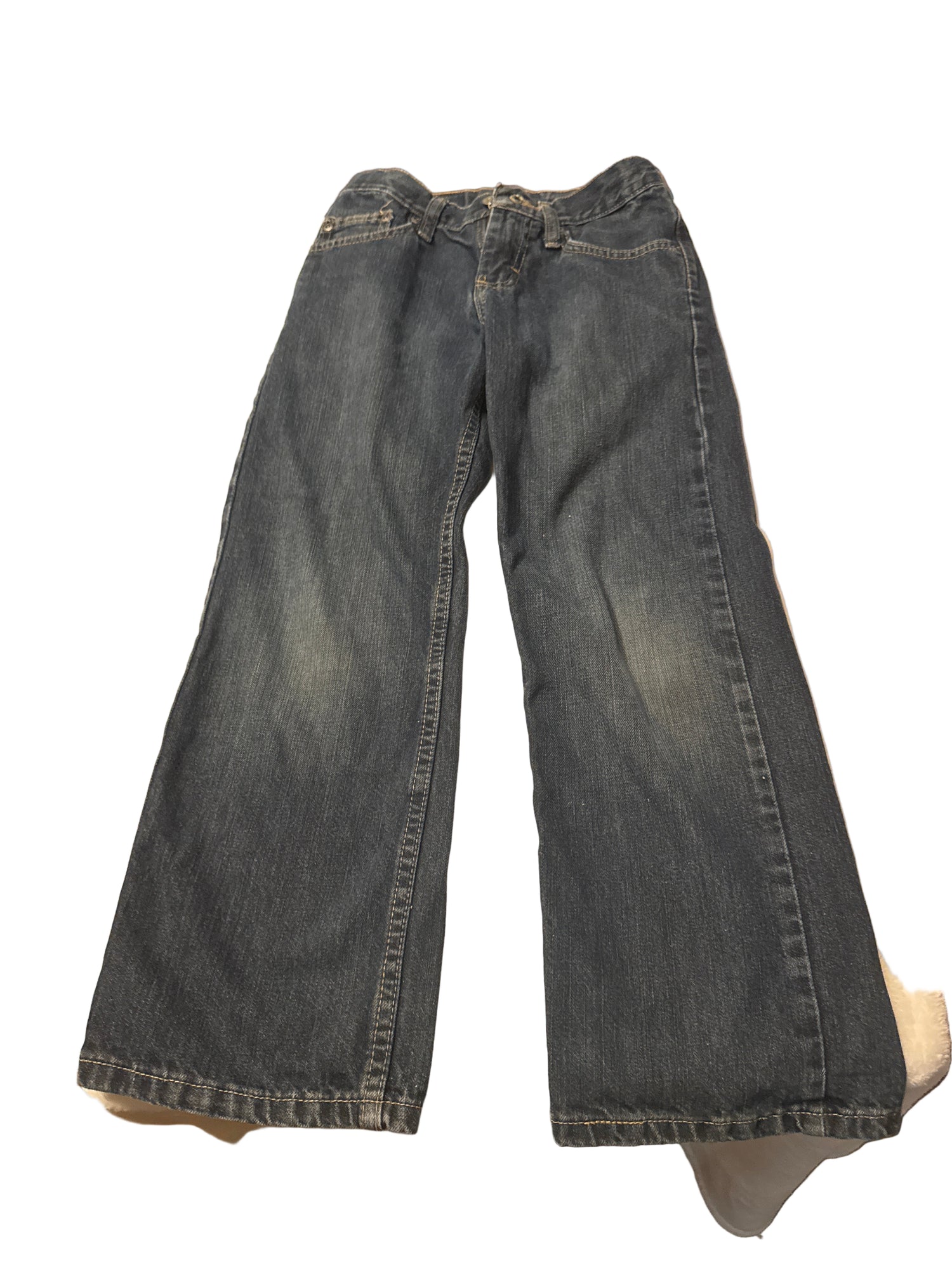 Pair of blue jeans on a white surface with a cluttered background