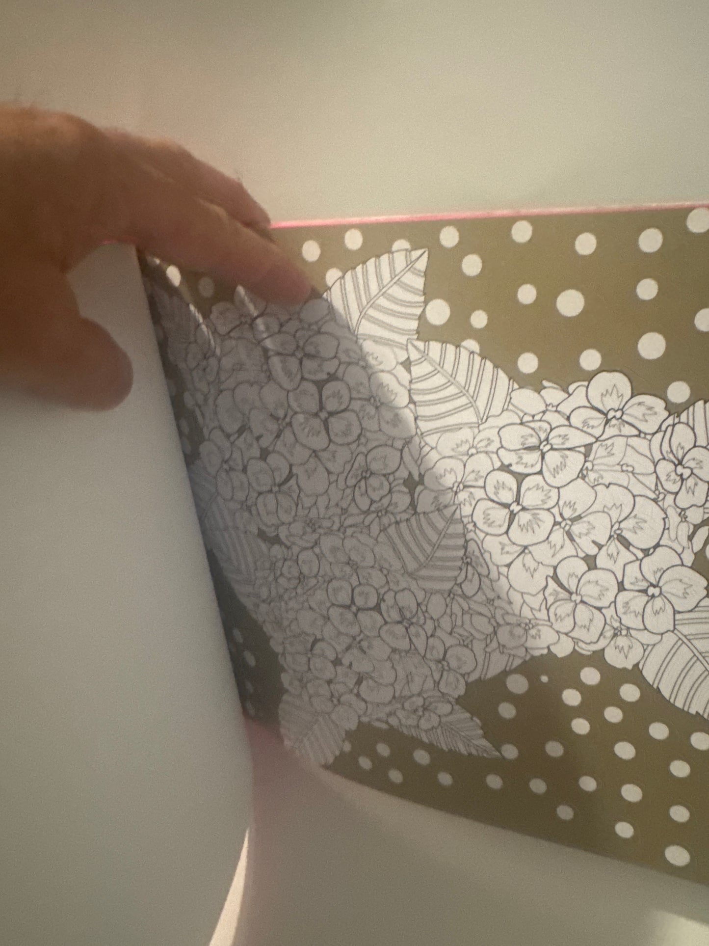 Person flipping through a book with creative flower coloring pages and polka dot background