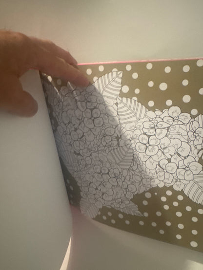 Person flipping through a book with creative flower coloring pages and polka dot background