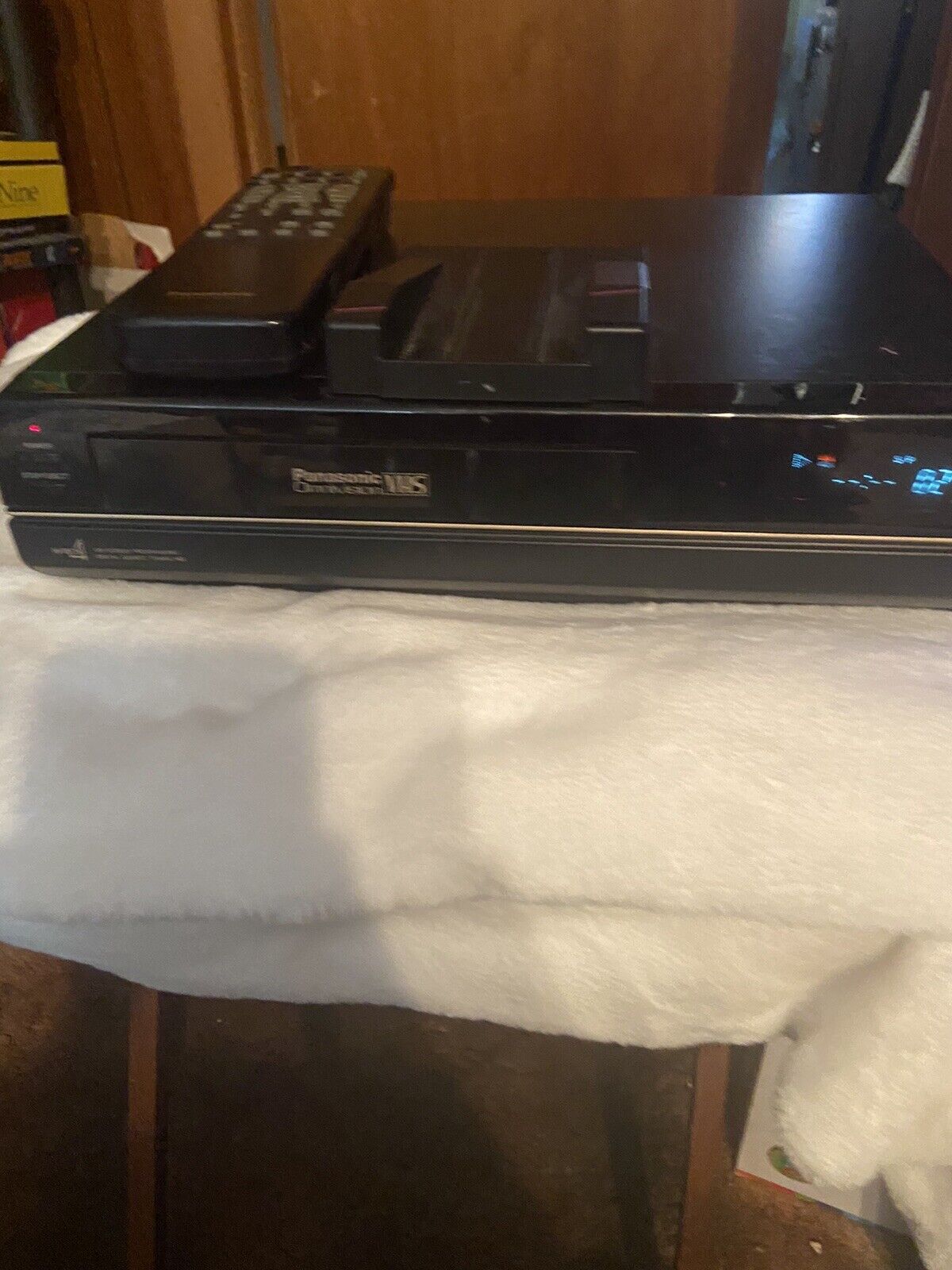 Panasonic OmniVision VHS player black VCR with remote on top sitting on white towel showing front panel