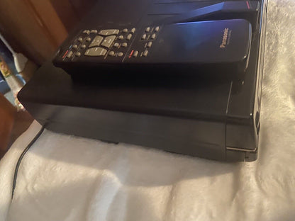 Panasonic OmniVision VHS player black vintage VCR with remote control on top resting on white blanket