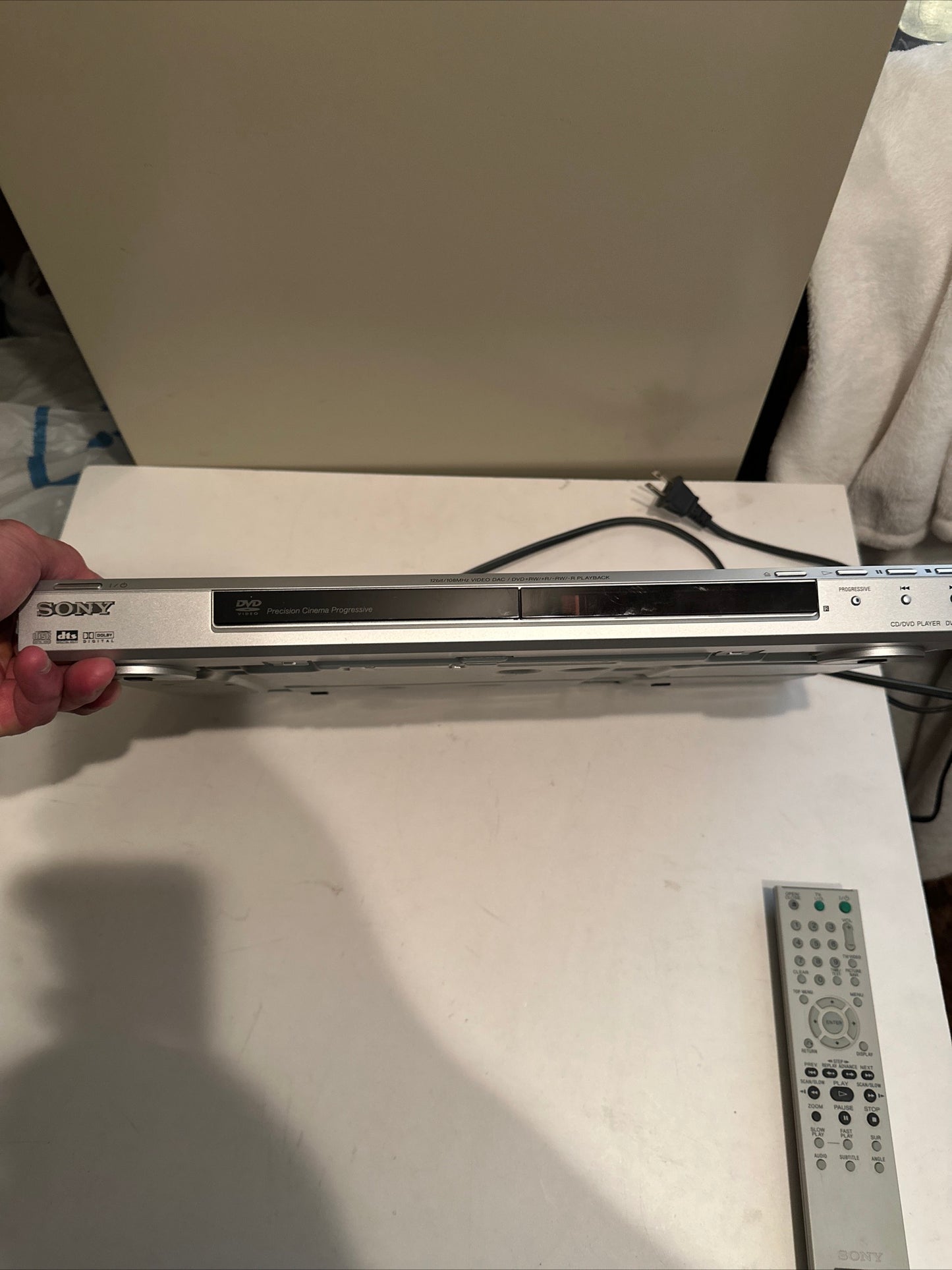 Sony DVD CD player held in hand with remote control on table, buy used DVD CD player online