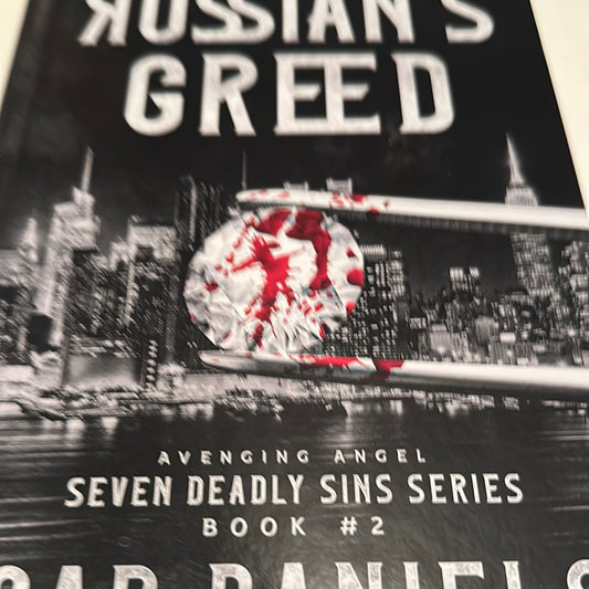 Close-up of The Russians Greed book cover featuring city skyline and blood-spattered target design